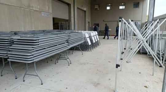 Point de retrait de matériel événementiel avec mobilier pliant et structure de barnum rangés en extérieur